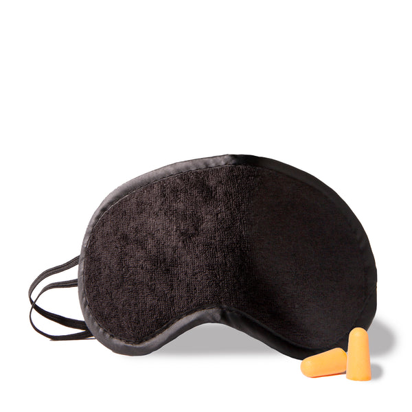 Black travel sleeping mask and orange yellow ear plugs designed by Tracker showing its soft plush texture and elastic.